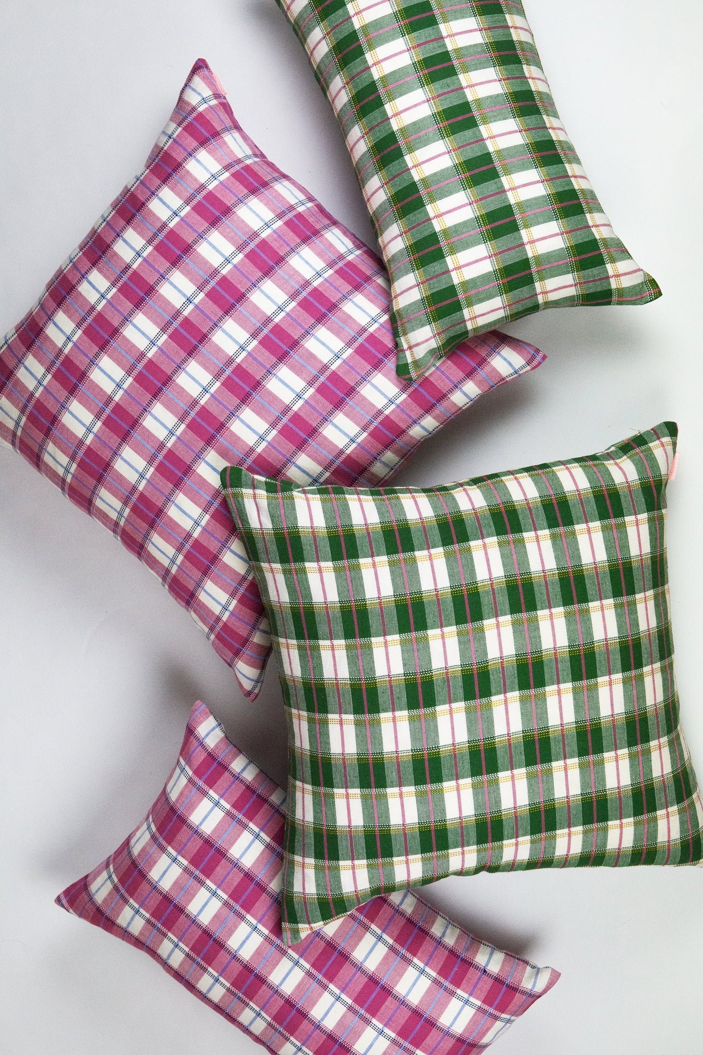 Throw pillows in pink and green gingham plaid patterns with woven cotton texture
