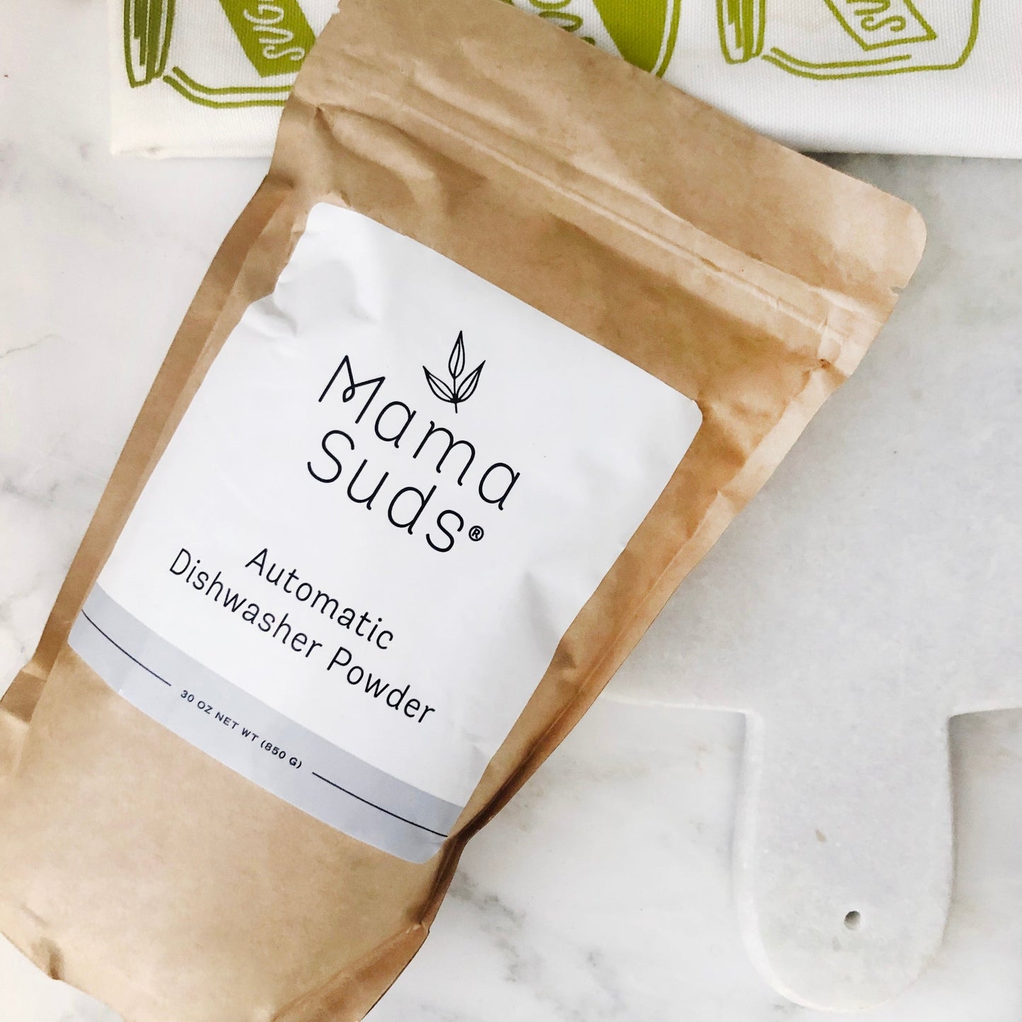 Kraft paper pouch of automatic dishwasher powder with white label on marble surface