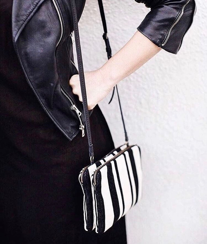 Black and white striped crossbody bag with silver hardware and adjustable strap