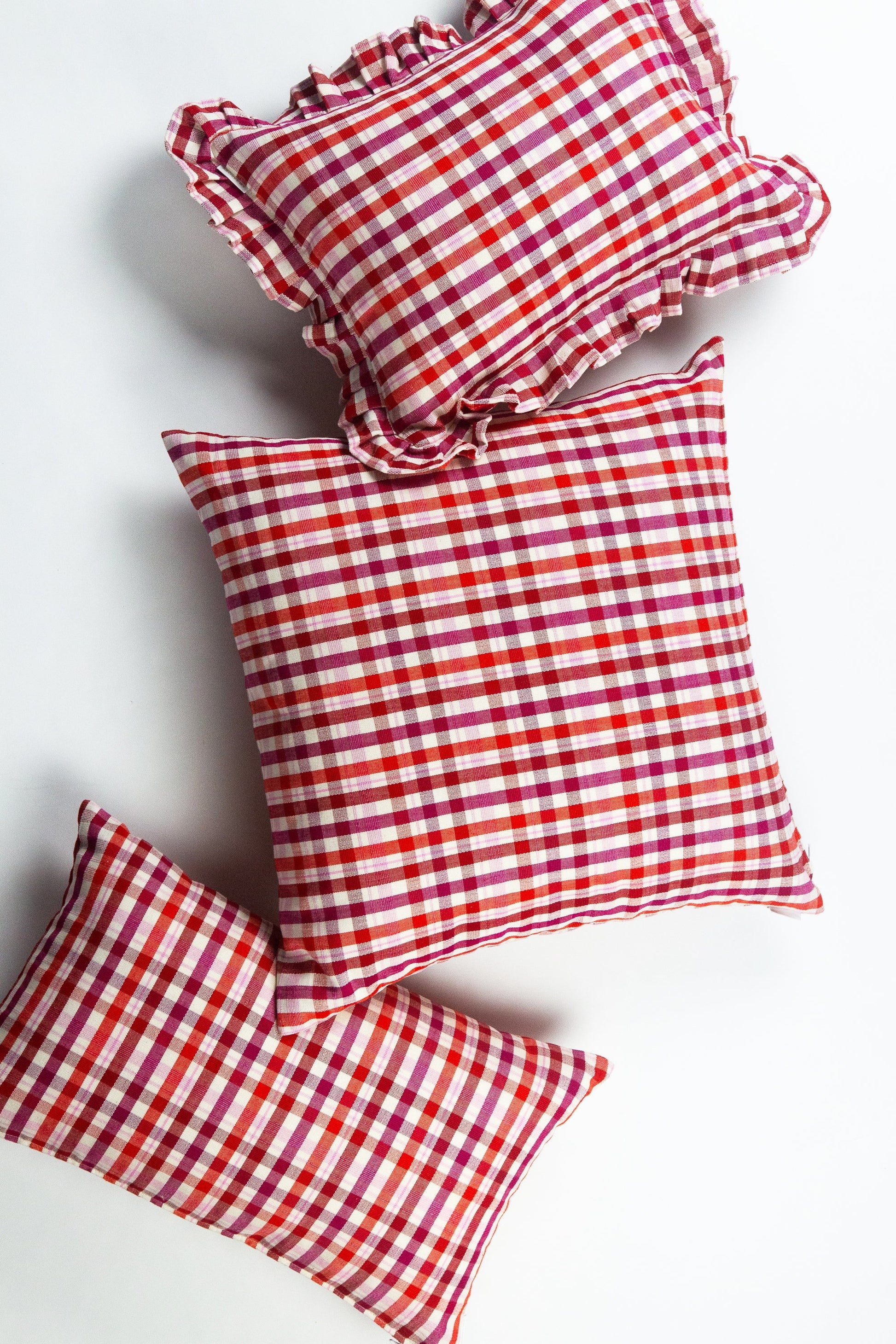 Red plaid bedding pillows with ruffled edges and gingham check pattern in cotton fabric