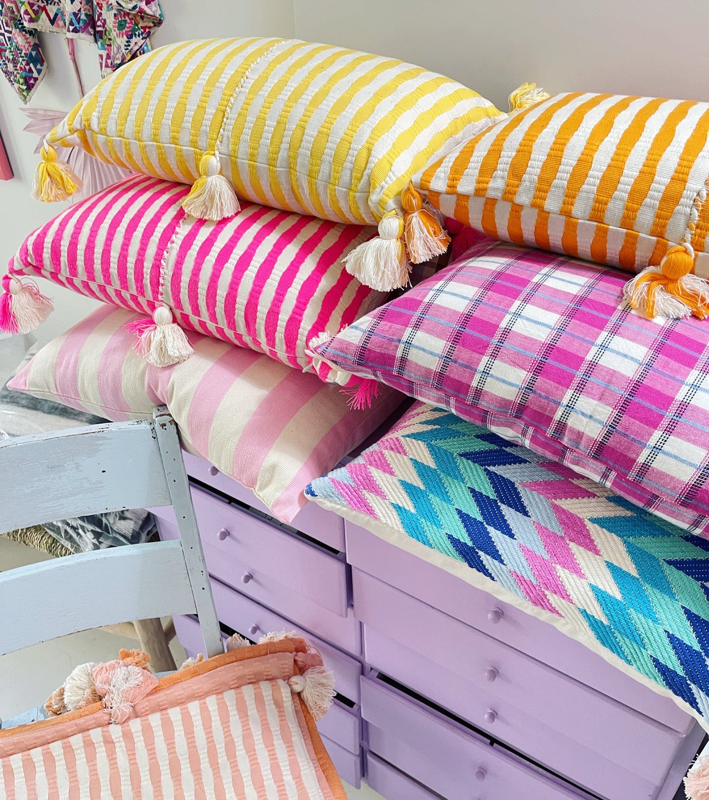 Striped and patterned throw pillows in yellow, pink, orange and multicolor gingham with tassel details