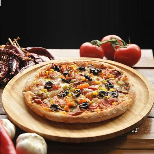 Bamboo round platter holding wood-fired pizza with vegetables, olives, and toppings, natural wood finish