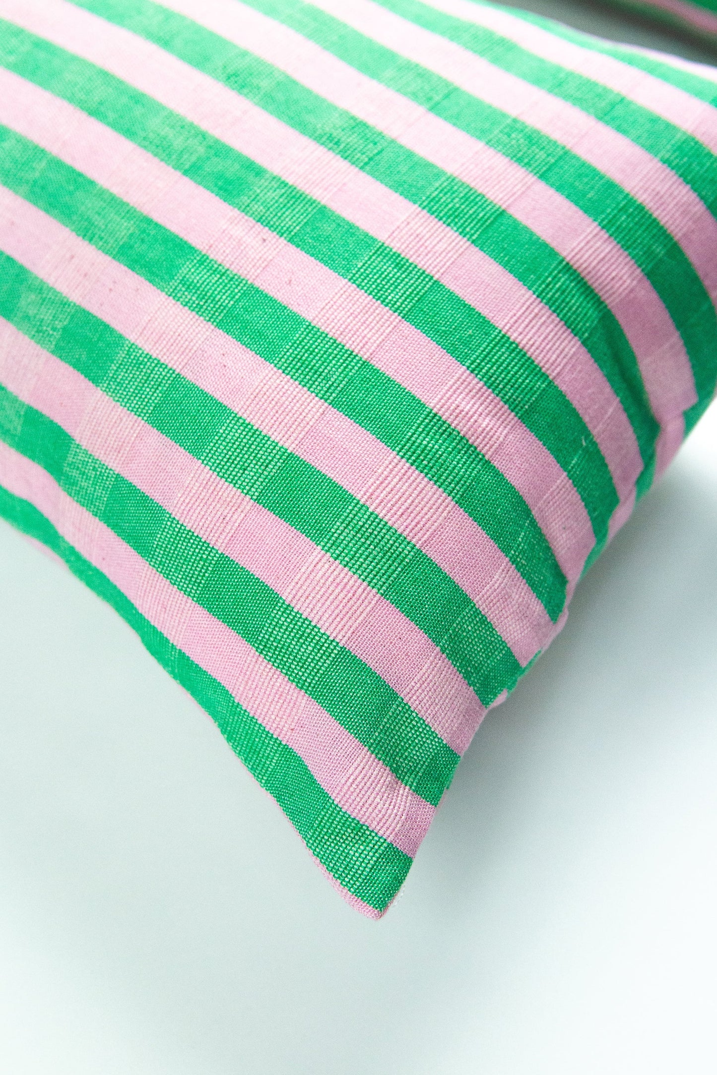 Green and pink striped organic cotton pillow with textured weave and diagonal fold detail