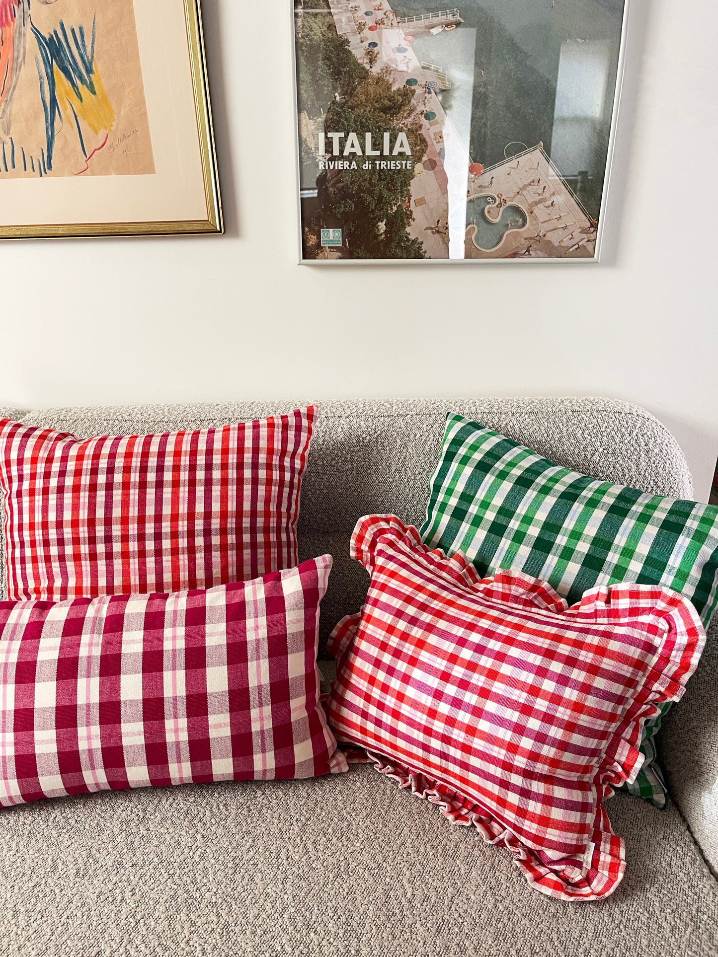 Red and white gingham plaid throw pillow with ruffled edges on gray sofa