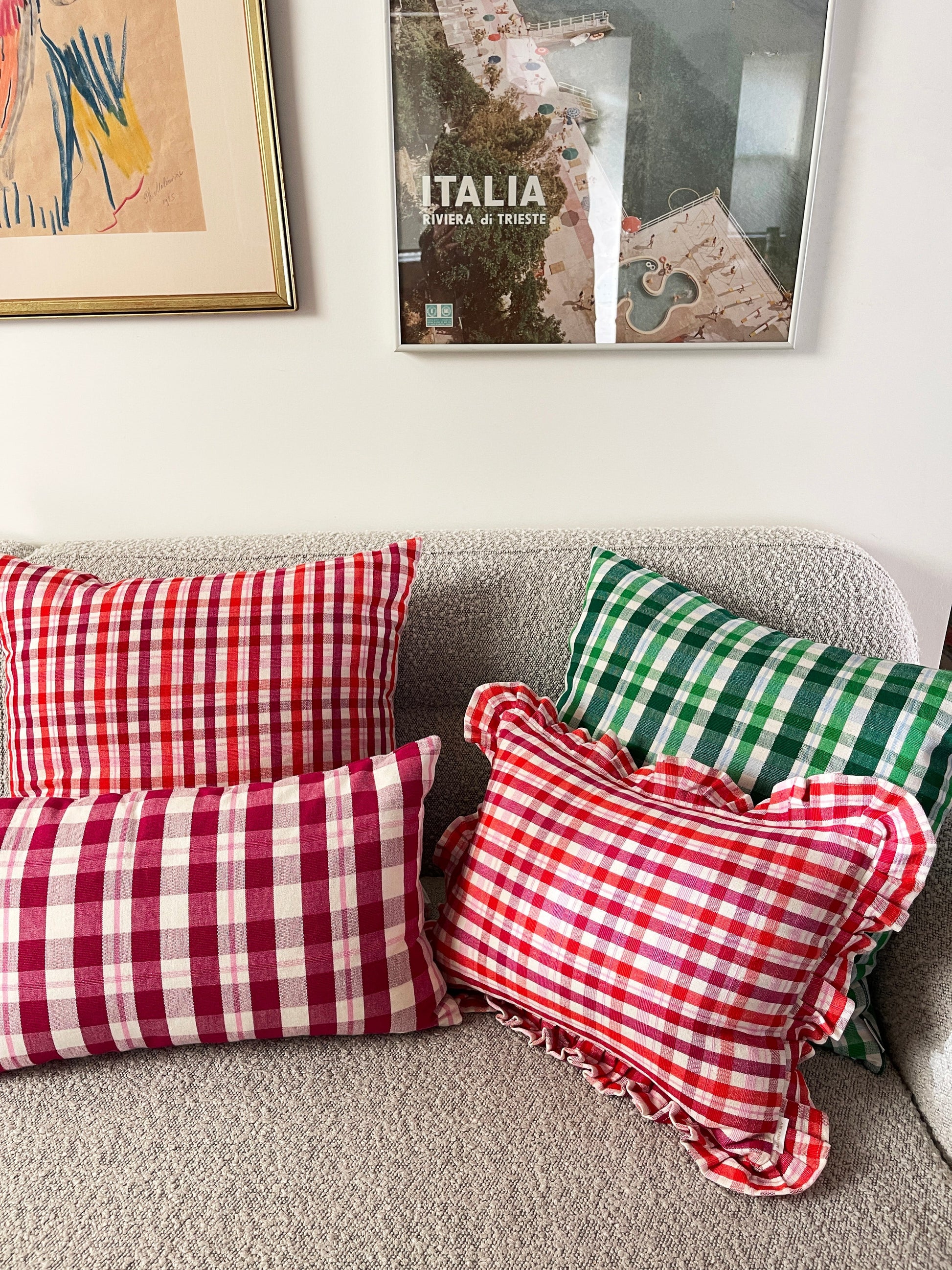 Red and white gingham plaid throw pillow with ruffled edges on gray sofa