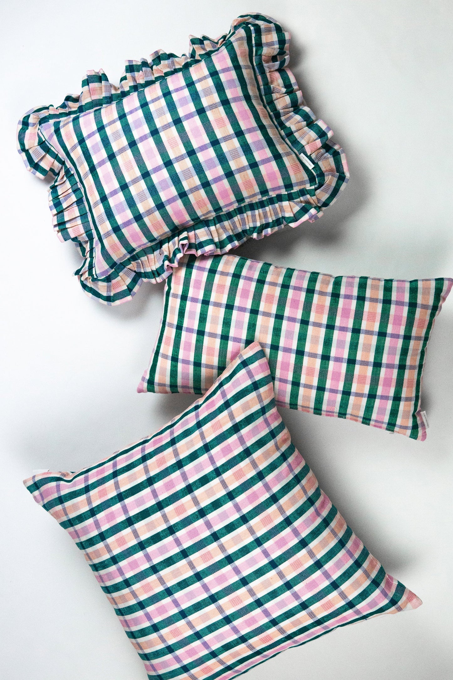 Plaid square throw pillows with teal and pink checkered pattern and ruffled edges in sustainable cotton fabric