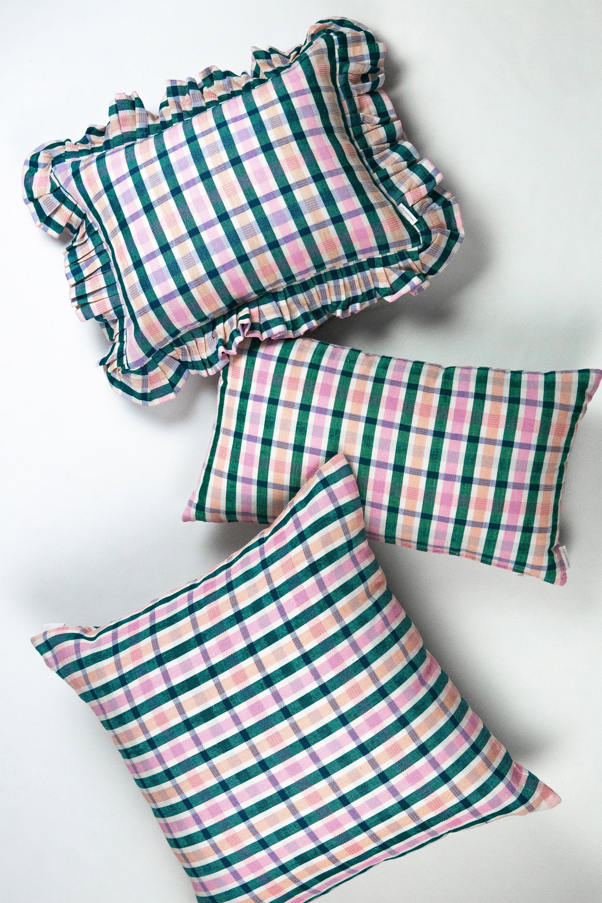 Plaid square throw pillows with teal and pink checkered pattern and ruffled edges in sustainable cotton fabric