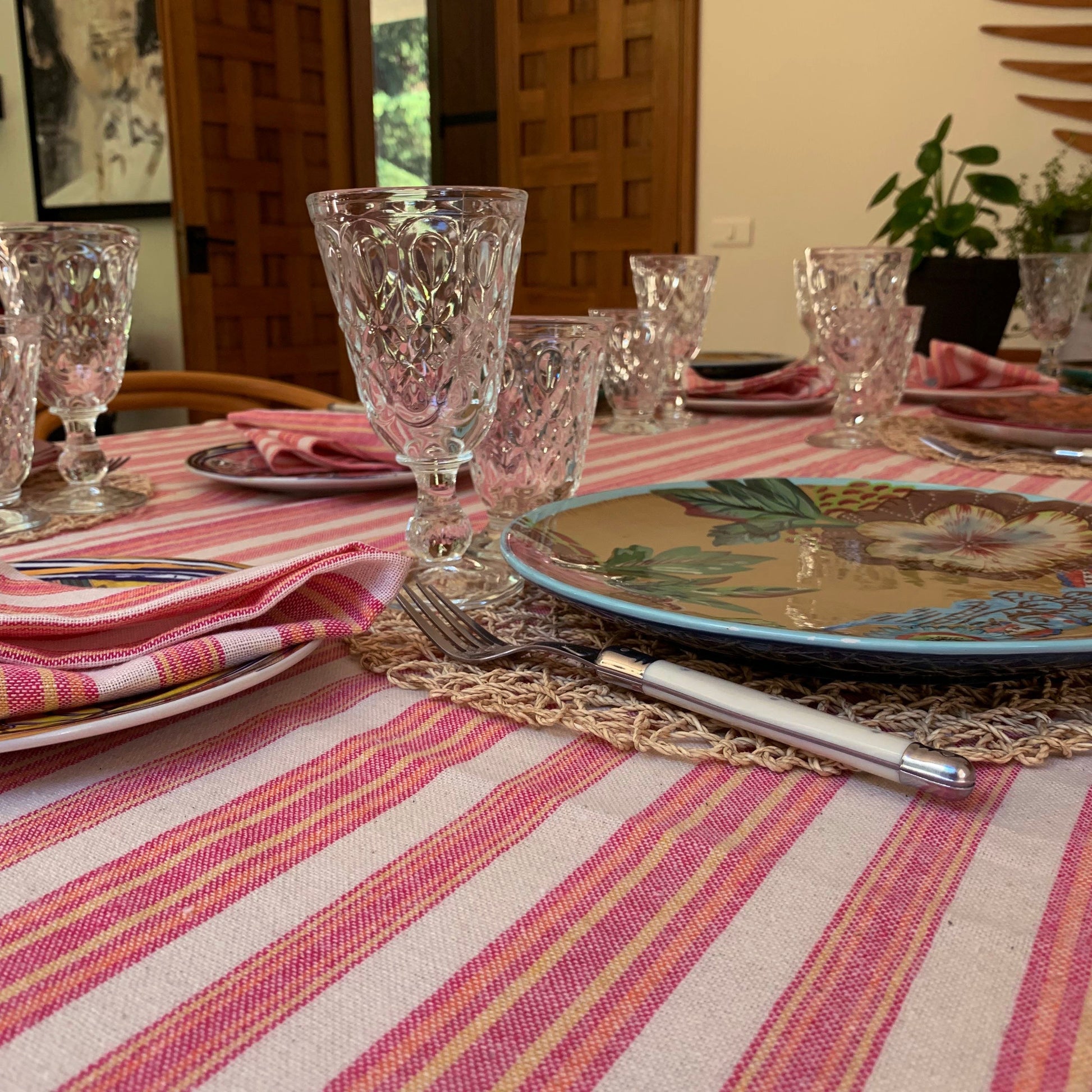Pink and cream striped linen tablecloth with coordinating napkins and natural fiber placemat