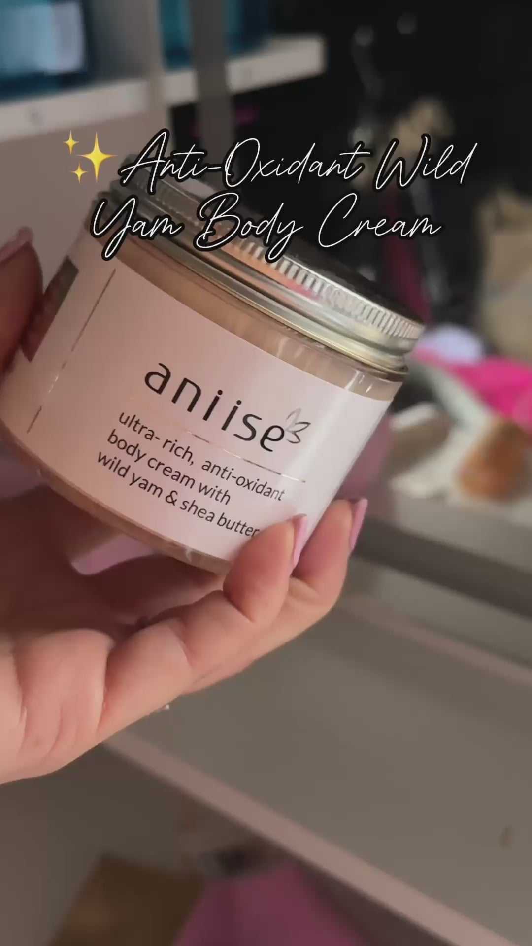 Pink glass jar anti-oxidant body cream with wild yam and shea butter in hand, natural skincare product