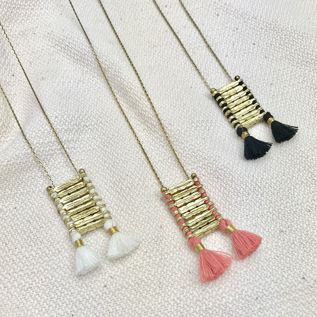 Anika Temple necklace with brass ladder pendant and colorful silk tassel charms in white, pink, and black