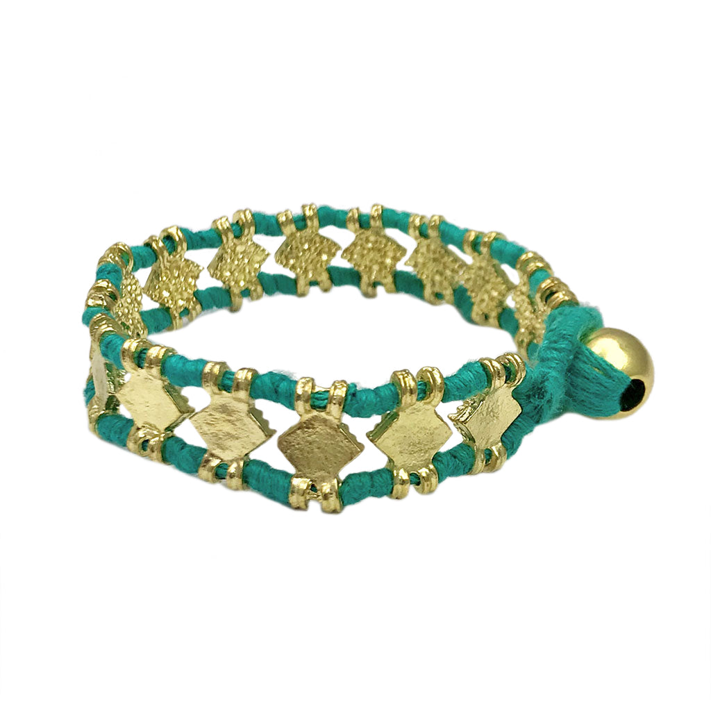 Teal woven bracelet with gold-plated brass charms and tassel closure, artisan jewelry accessory
