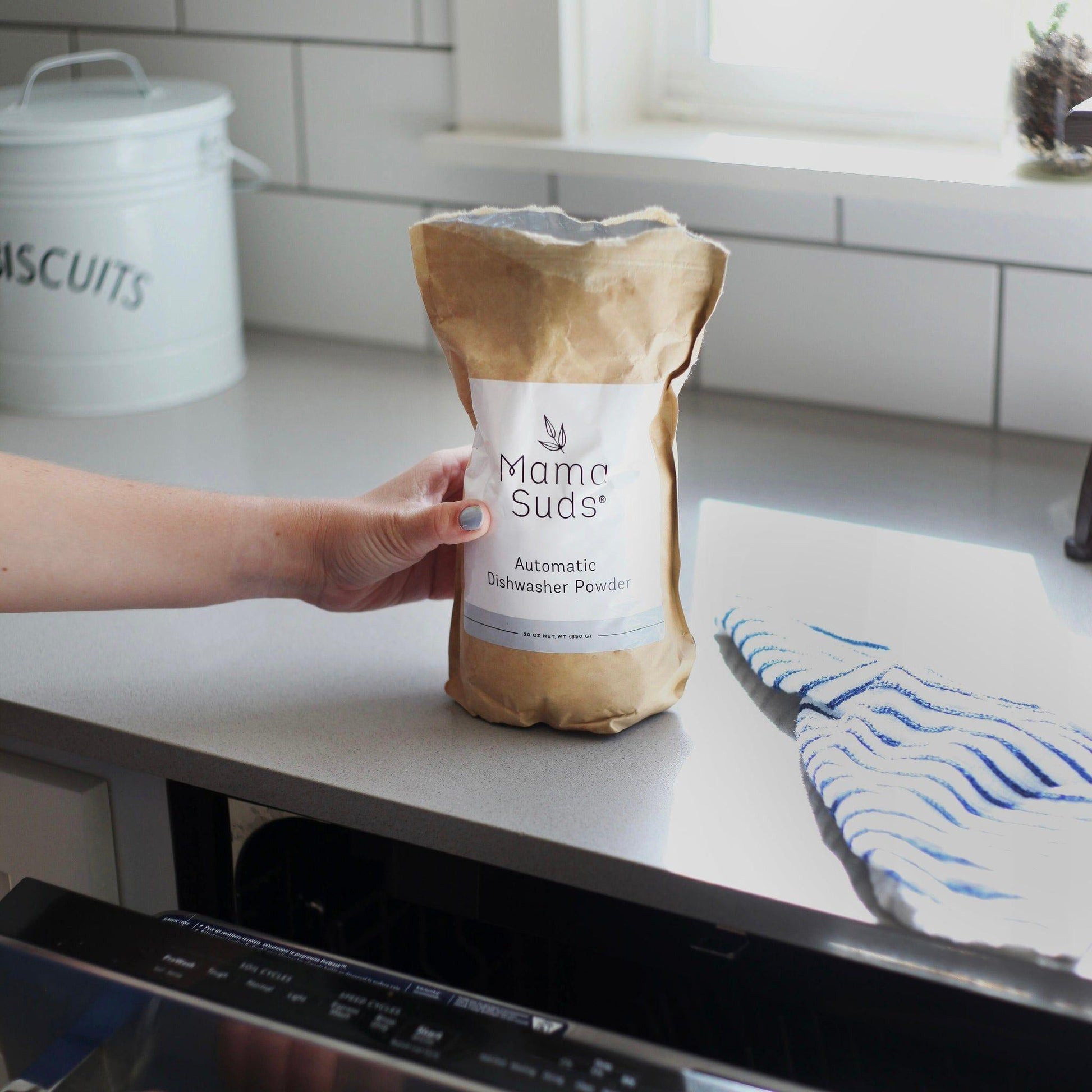 Eco-friendly automatic dishwasher powder in kraft paper packaging with white label on kitchen counter