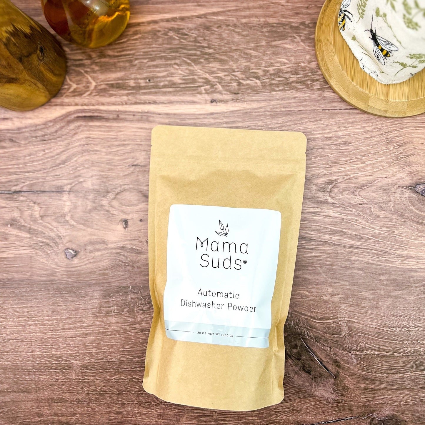 Kraft paper pouch of automatic dishwasher powder with white label on wooden surface