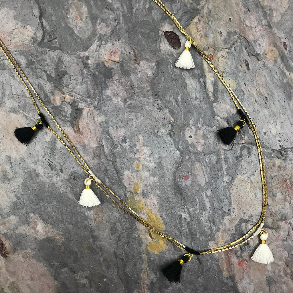Gold cord necklace with white and black tassel charms, bohemian jewelry accessory with metallic accents