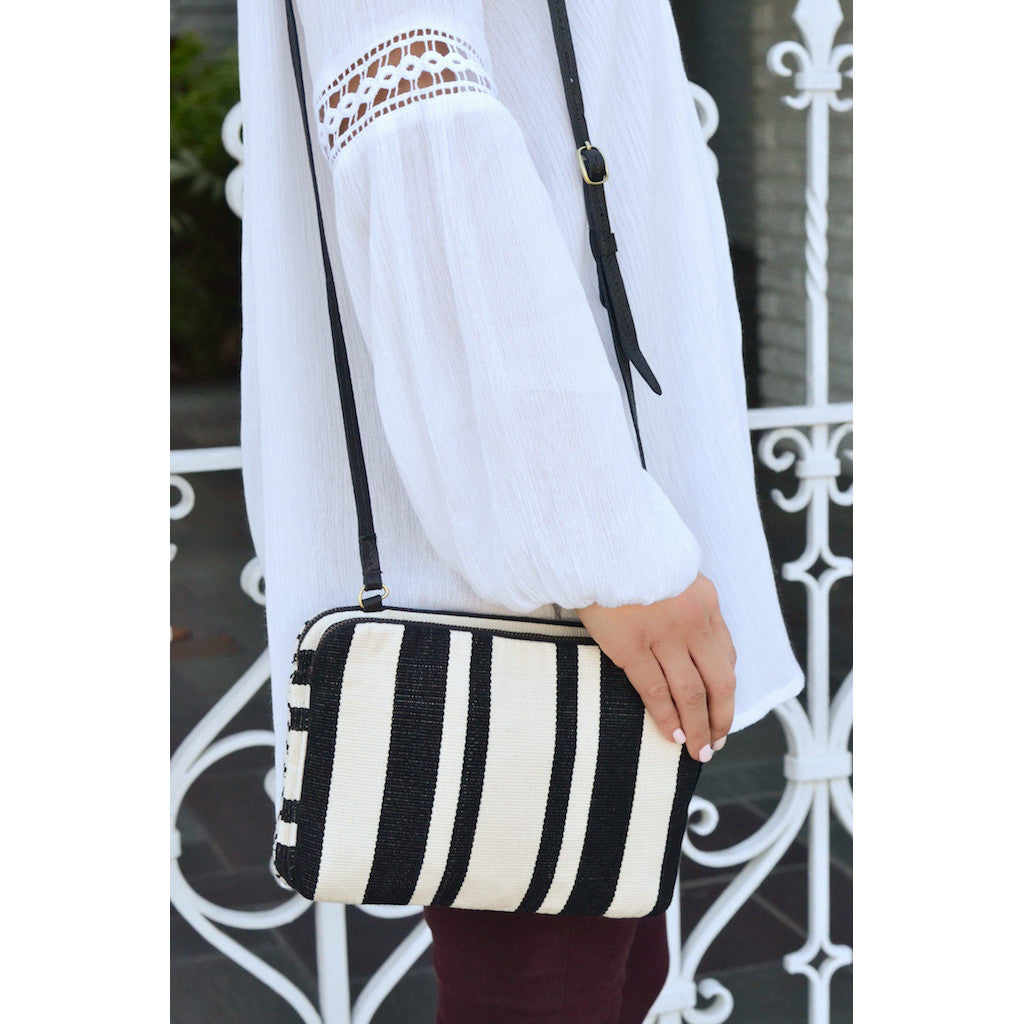 Black and cream striped woven crossbody bag with adjustable strap and structured design