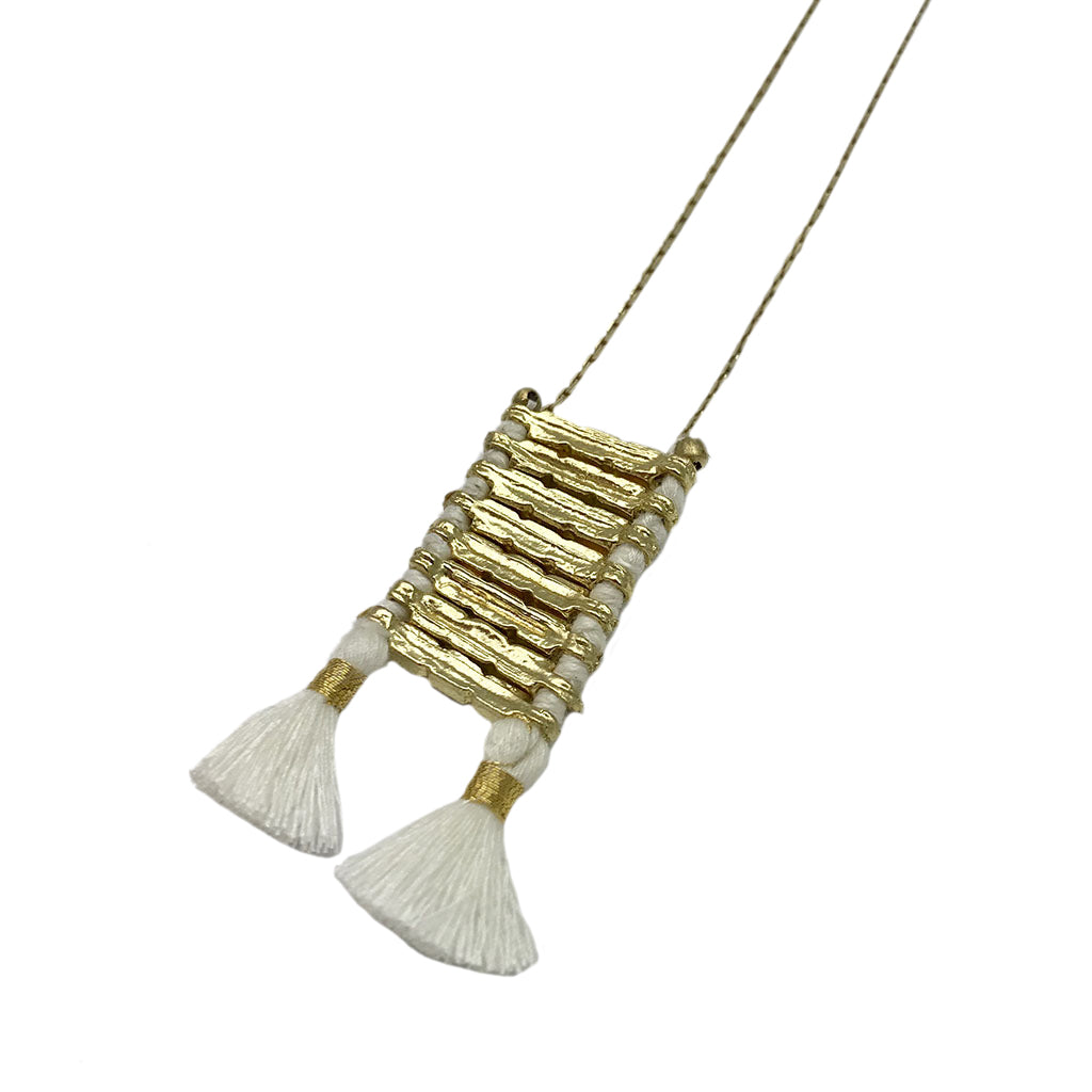 Gold and cream tassel necklace with textured metallic pendant and white silk fringe details